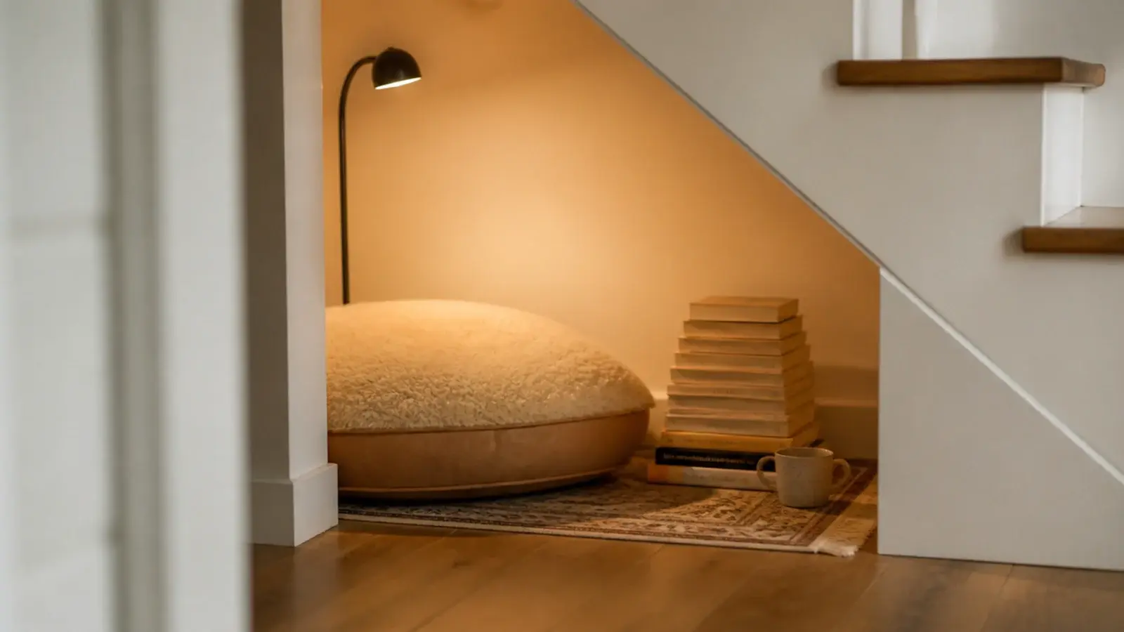 floor cushion rug and lamp arranged in an open under stairs nook