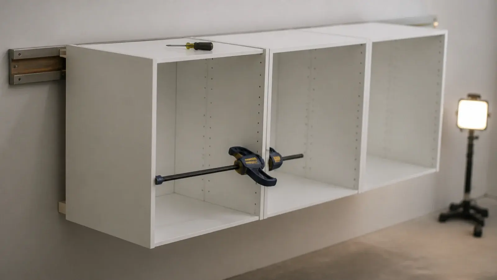 row of cabinet carcasses hung on a rail and clamped together for joining