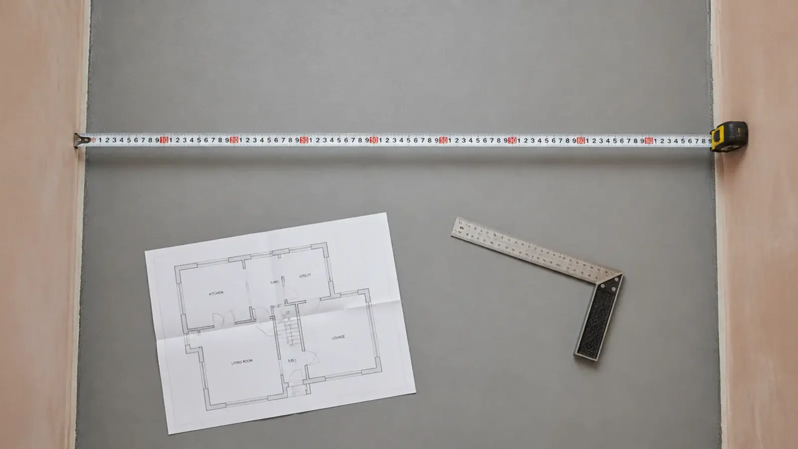 tape measure stretched across a slim laundry floor between two plastered walls