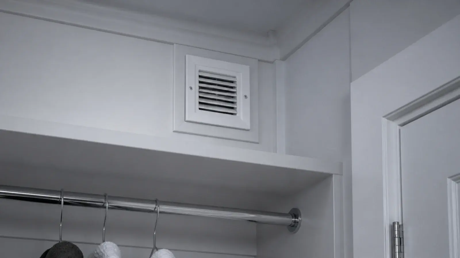 small white grille set high in a laundry cupboard wall near the ceiling