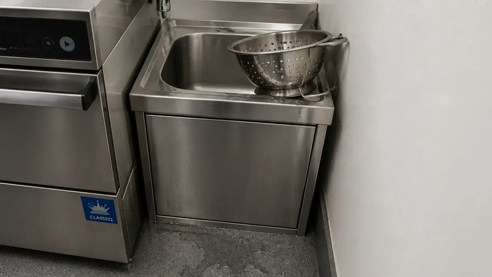 small utility sink squeezed at the end of a run with no drainer
