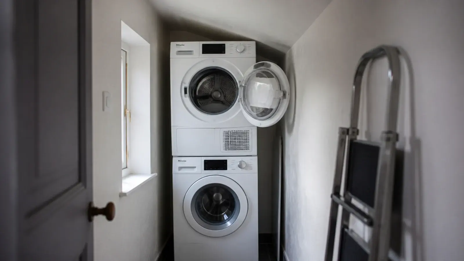 stacked laundry pair standing short of a sloping utility ceiling