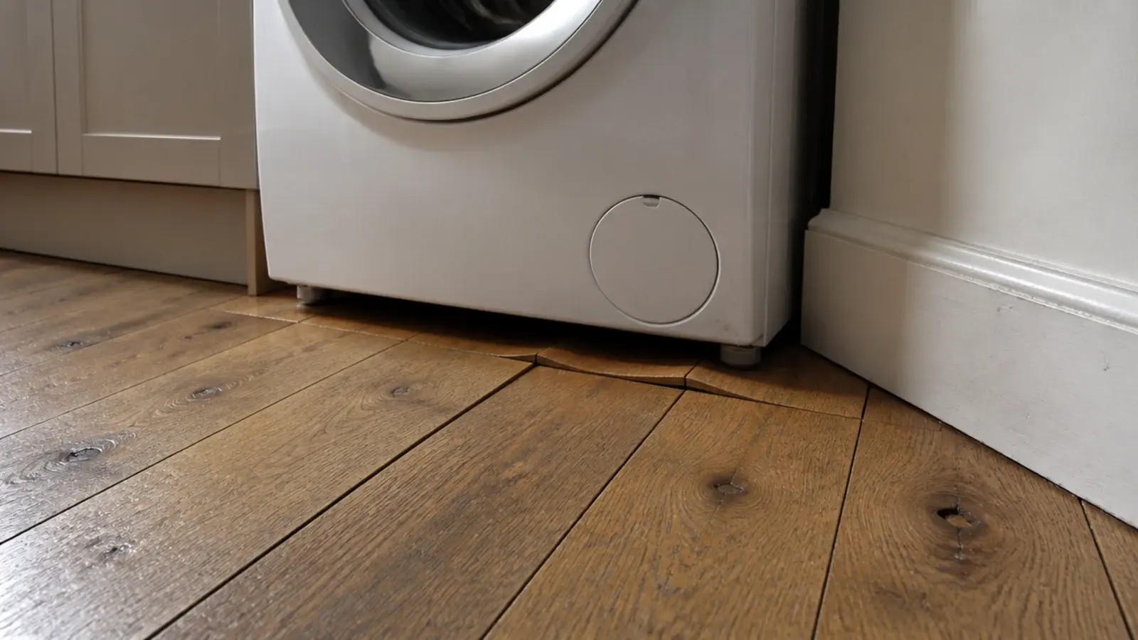 cupped solid oak boards running tight under a utility washing machine