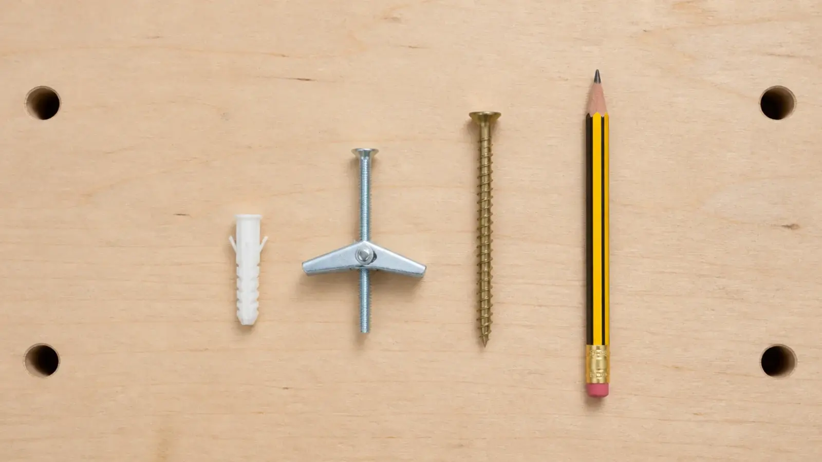 plastic wall plug toggle bolt and wood screw laid out for comparison