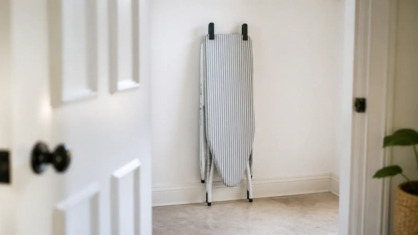 ironing board held flat to a wall by two black spring clips