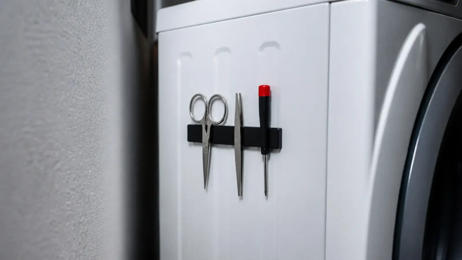 magnetic knife strip fixed to a washer side holding scissors and tools