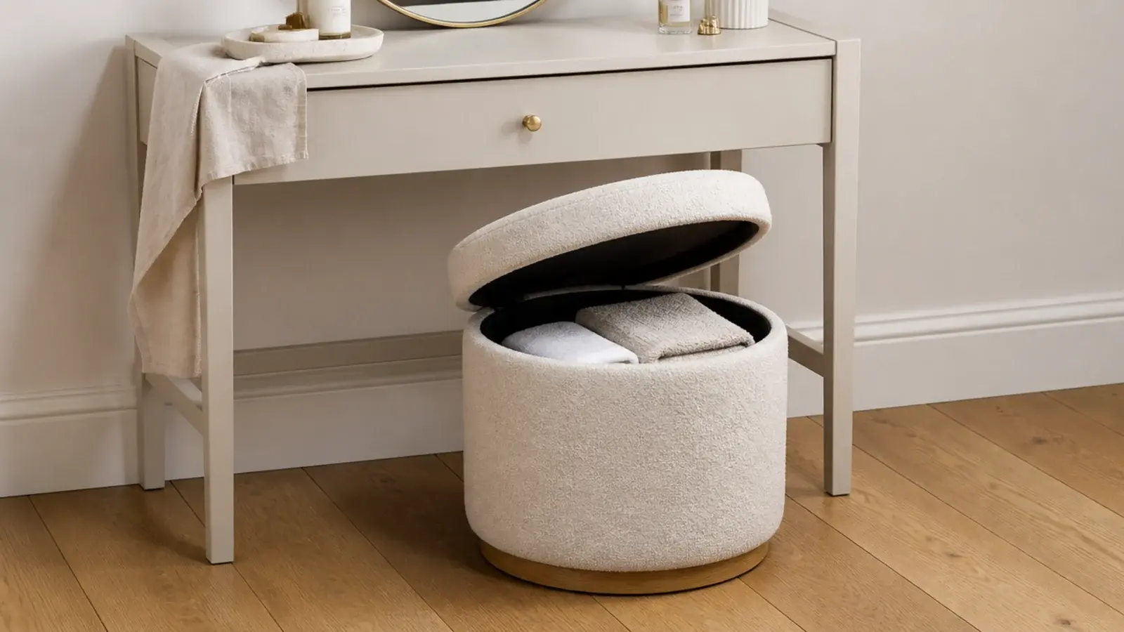 lift lid stool tucked under a small vanity holding folded towels