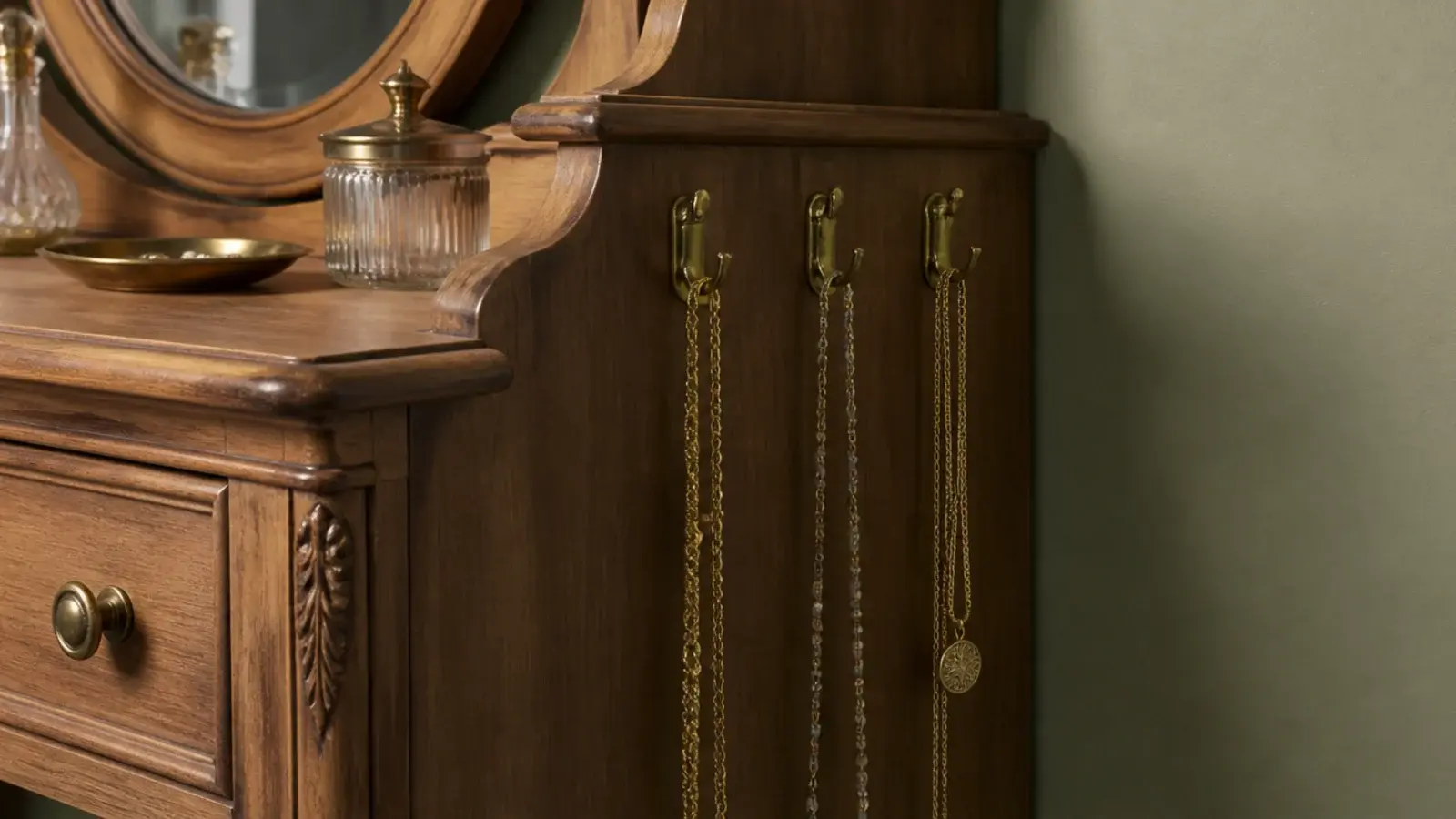 small brass hooks holding long necklaces beside a bedroom dressing table