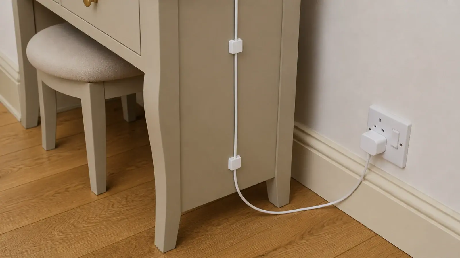 charging cable clipped down the rear leg of a bedroom vanity table