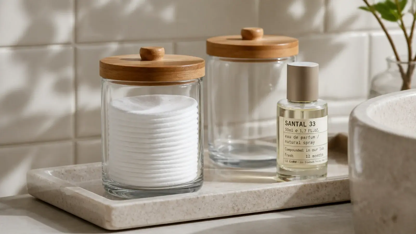 lidded glass jar of cotton pads sitting on a vanity tray