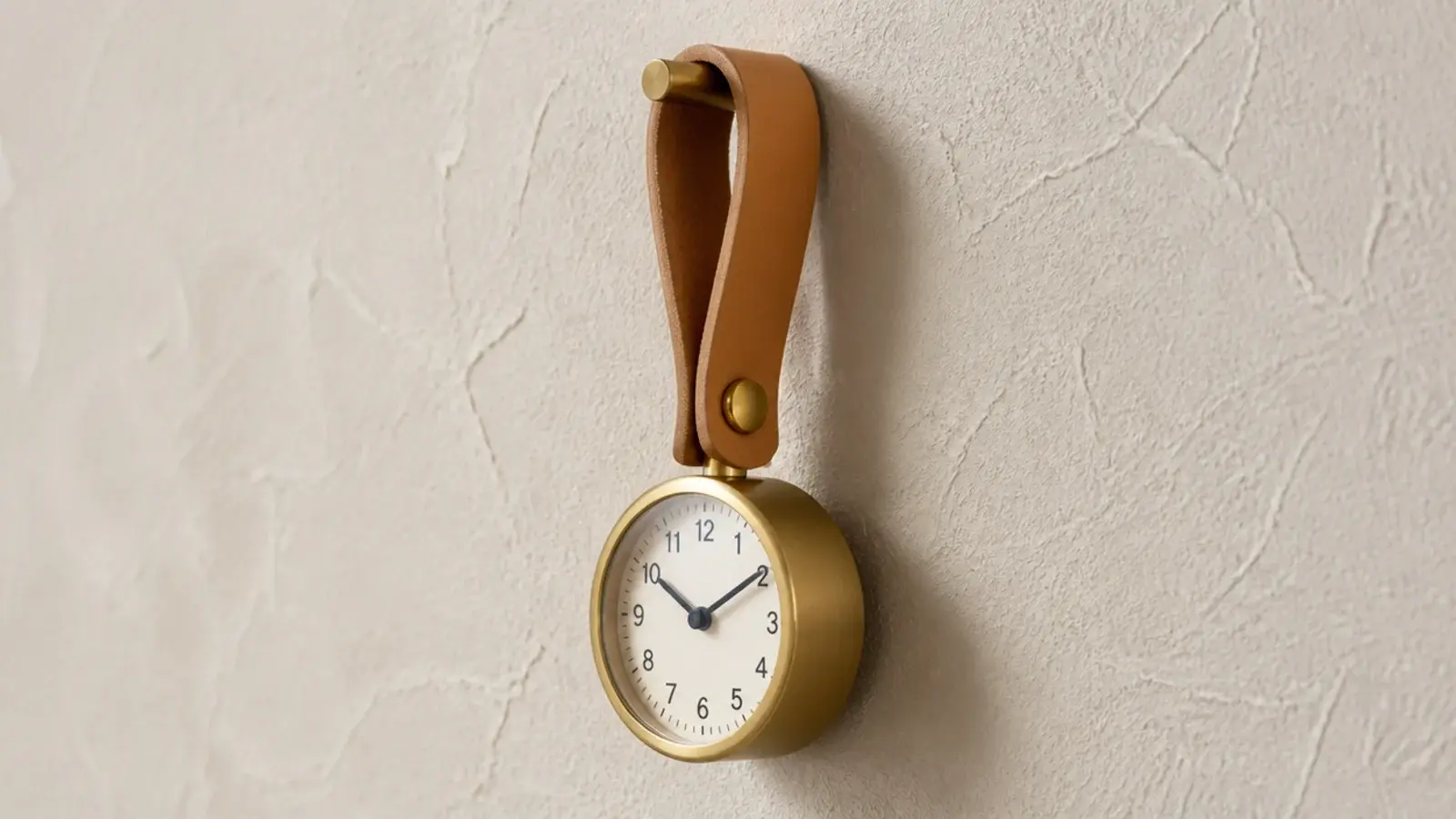 small clock suspended from a leather strap looped over a hook
