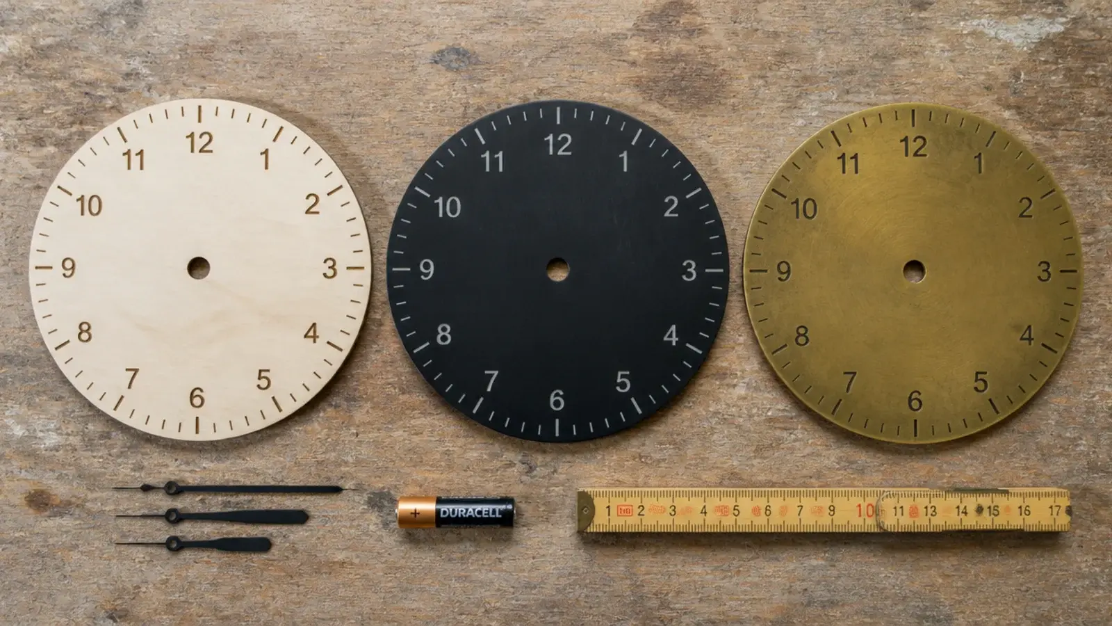 three clock faces of different styles laid out on a workbench