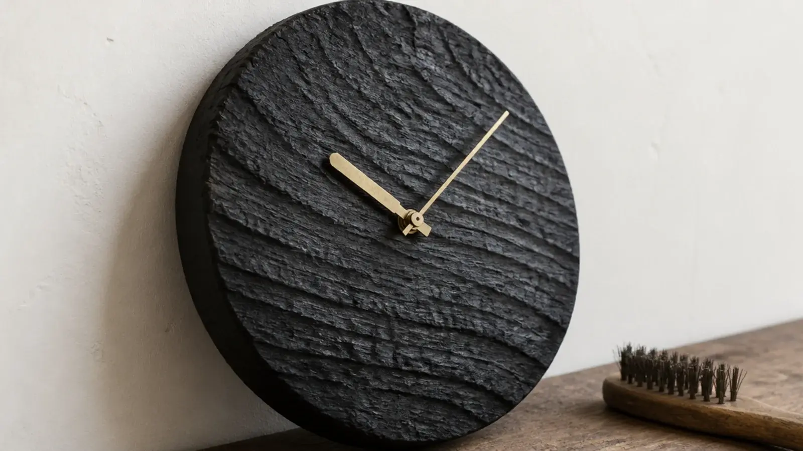 charred timber clock face with a matte blackened rippled surface