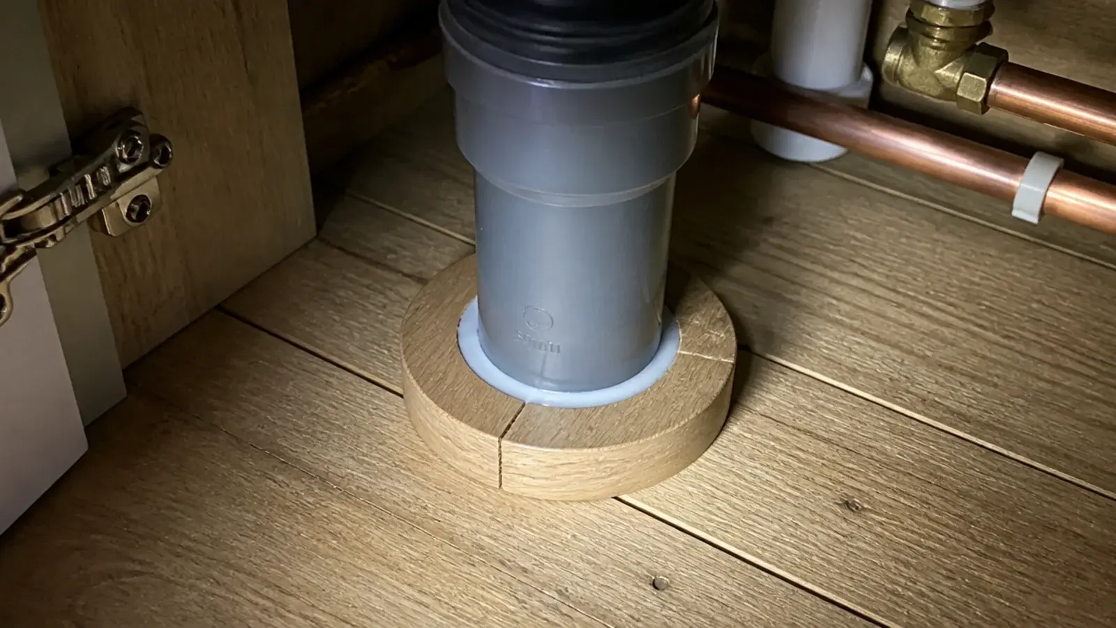pipe collar and sealant finishing a waste pipe hole in kitchen boards