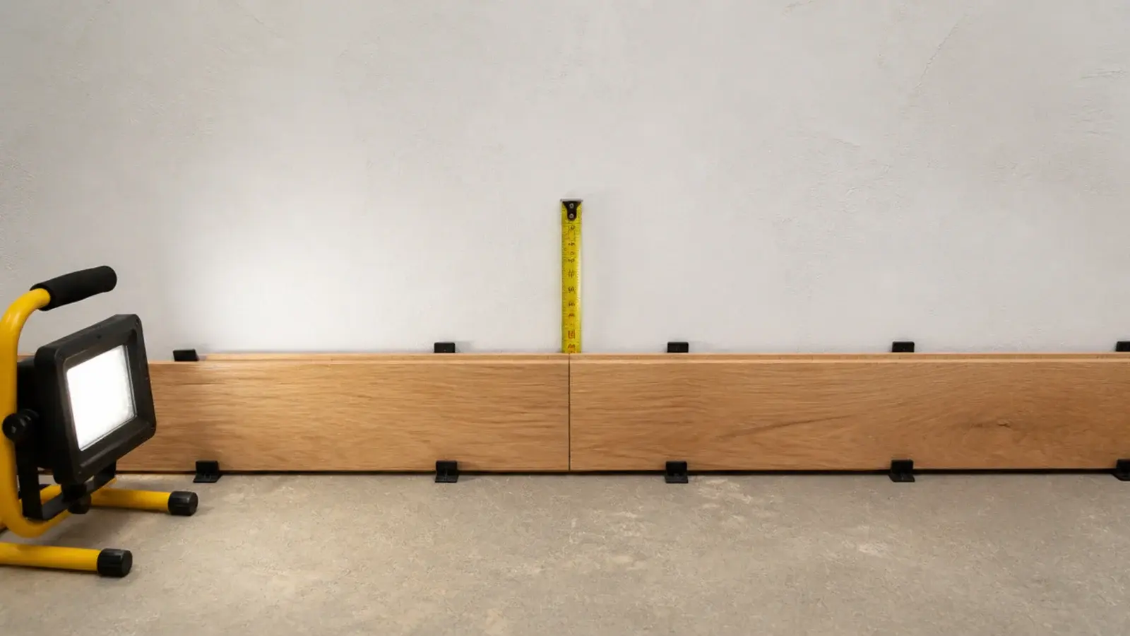 first row of planks held off the wall by evenly placed plastic spacers