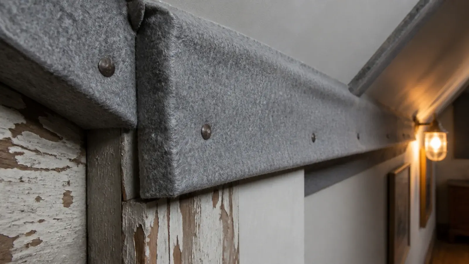 soft felt padding wrapped around a low attic rafter corner beside a doorway