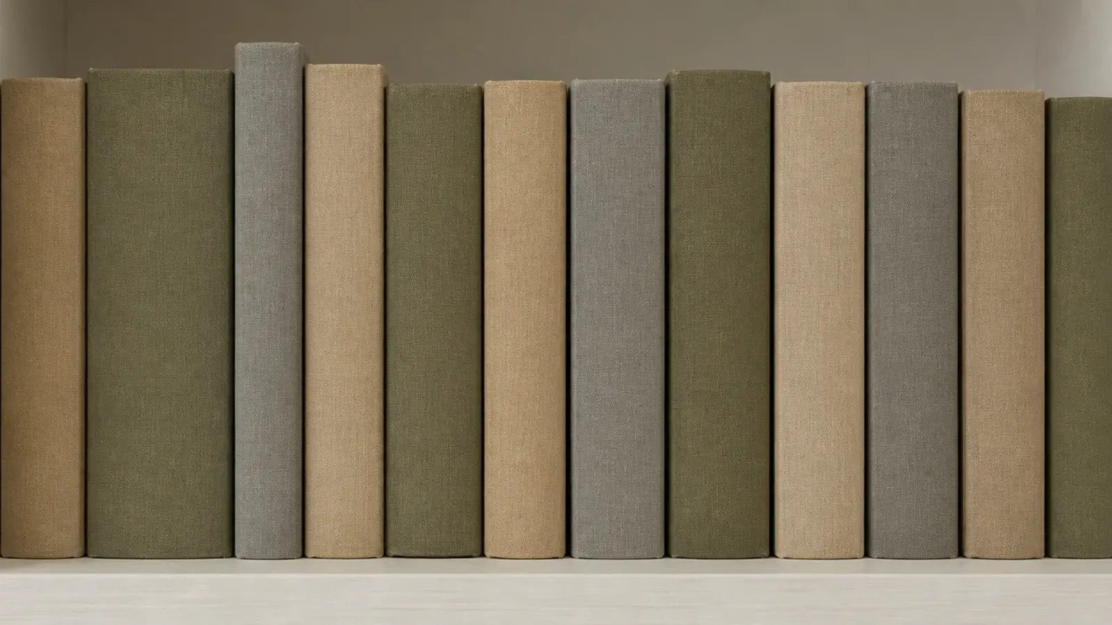 cloth bound spines in muted tones on a calm bedroom bookshelf