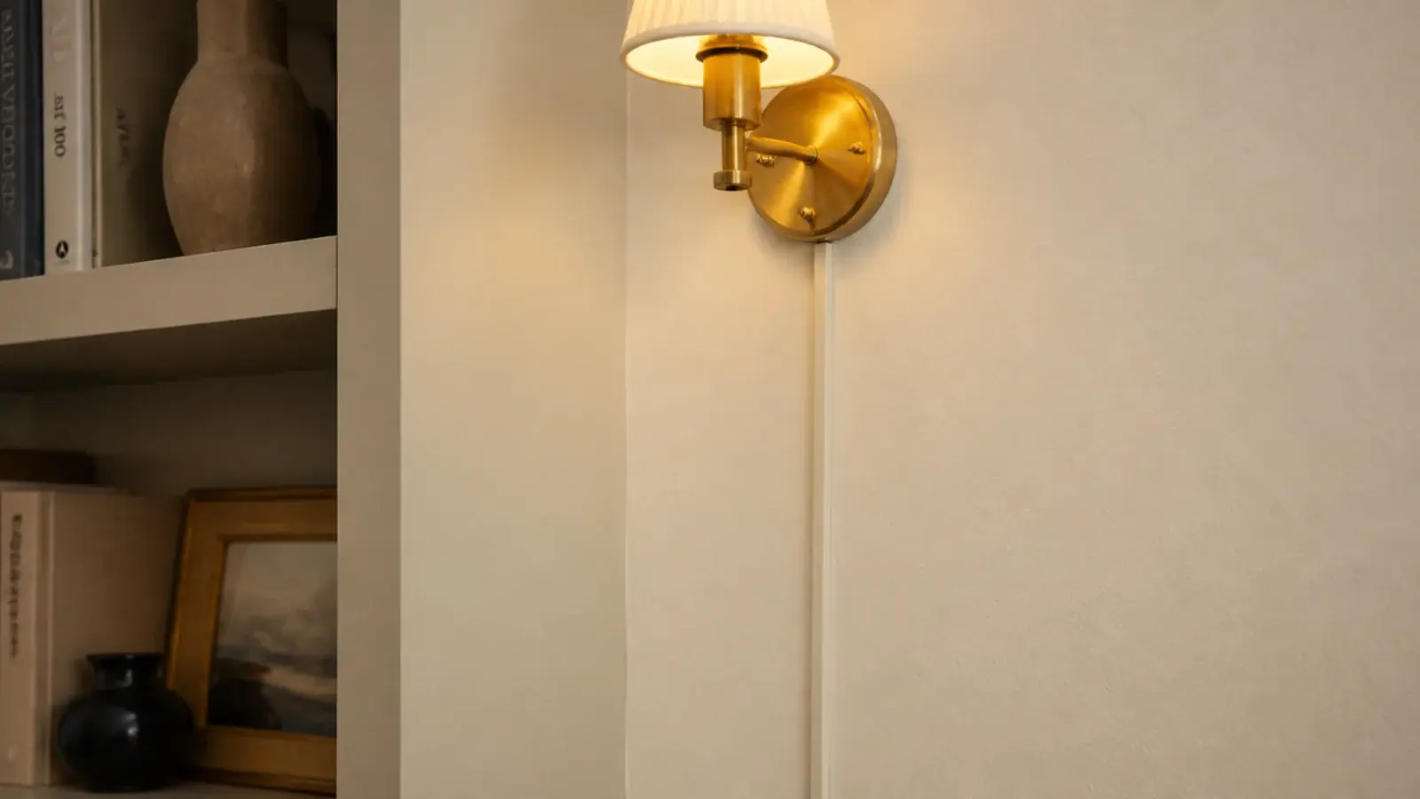 lamp cord hidden inside a painted channel beside styled bookshelves