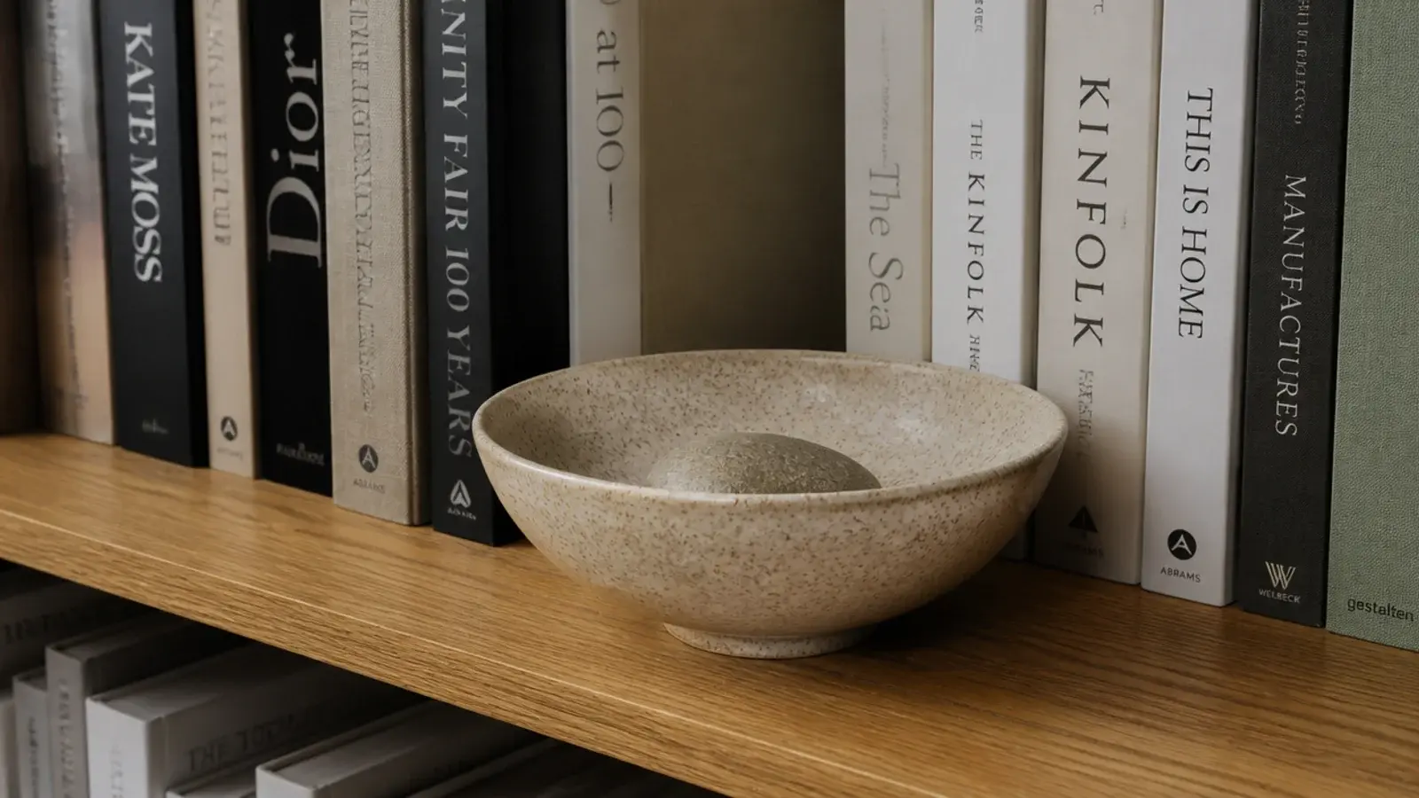 wide shallow stoneware bowl breaking a long row of upright books