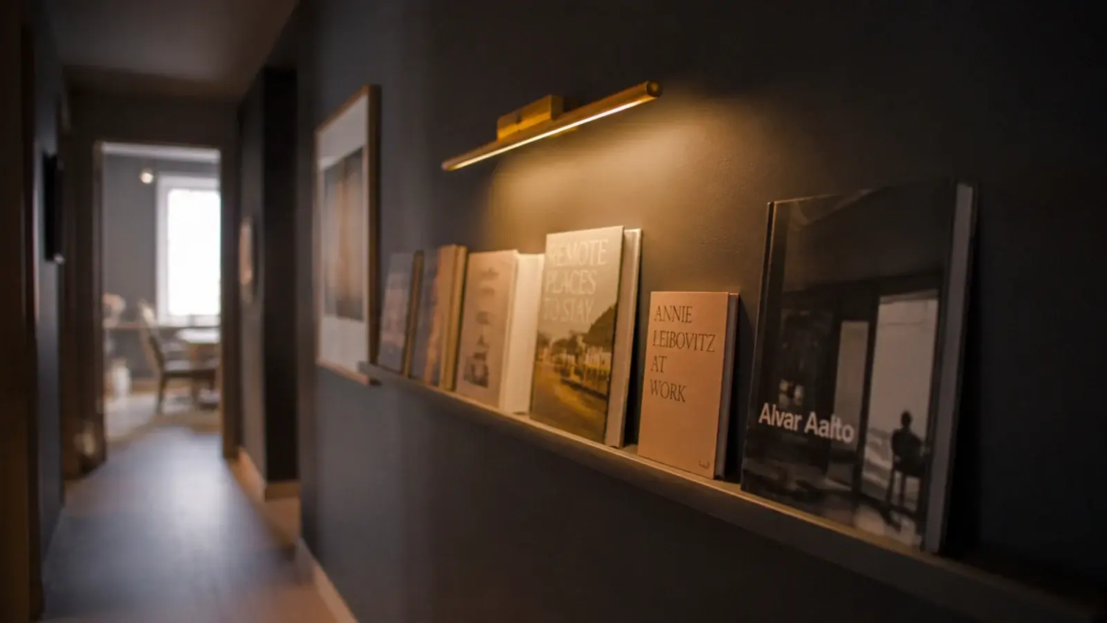 hallway book ledge lit by a small brass picture light above it