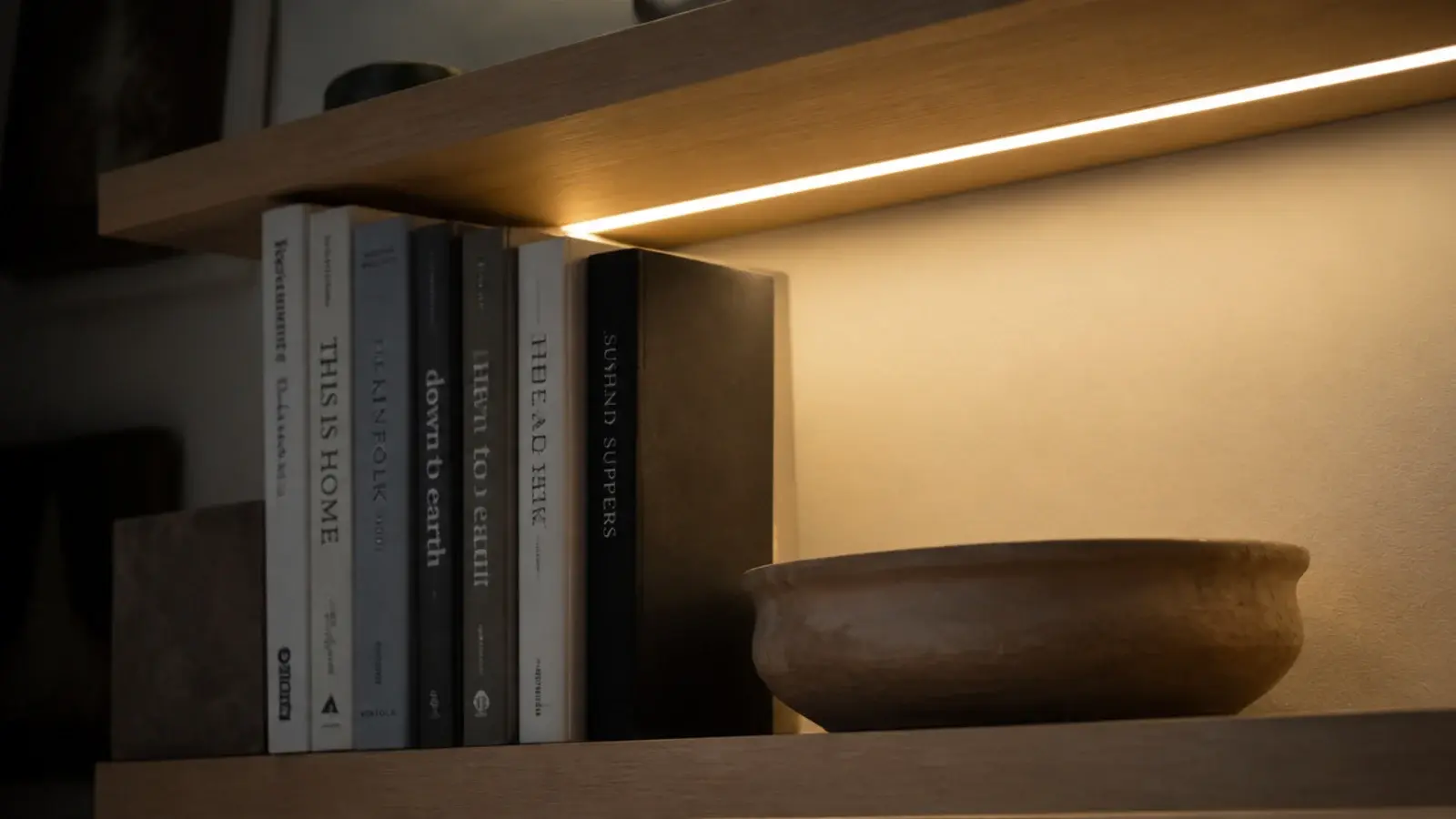 warm led strip under a floating shelf lighting the books below