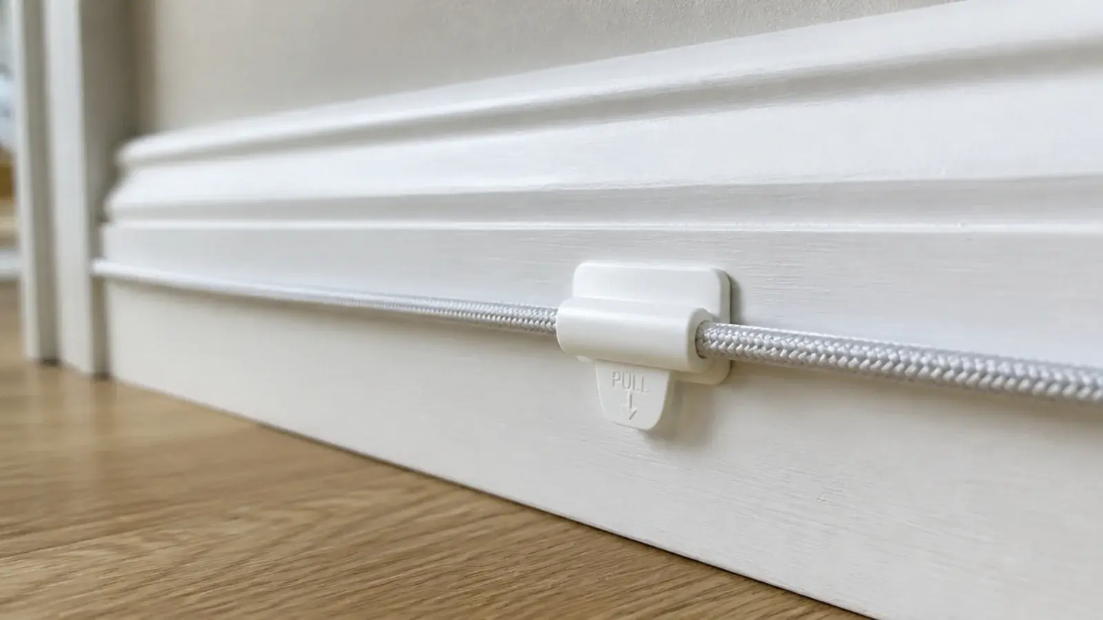 removable adhesive clip holding a charging cable along a skirting