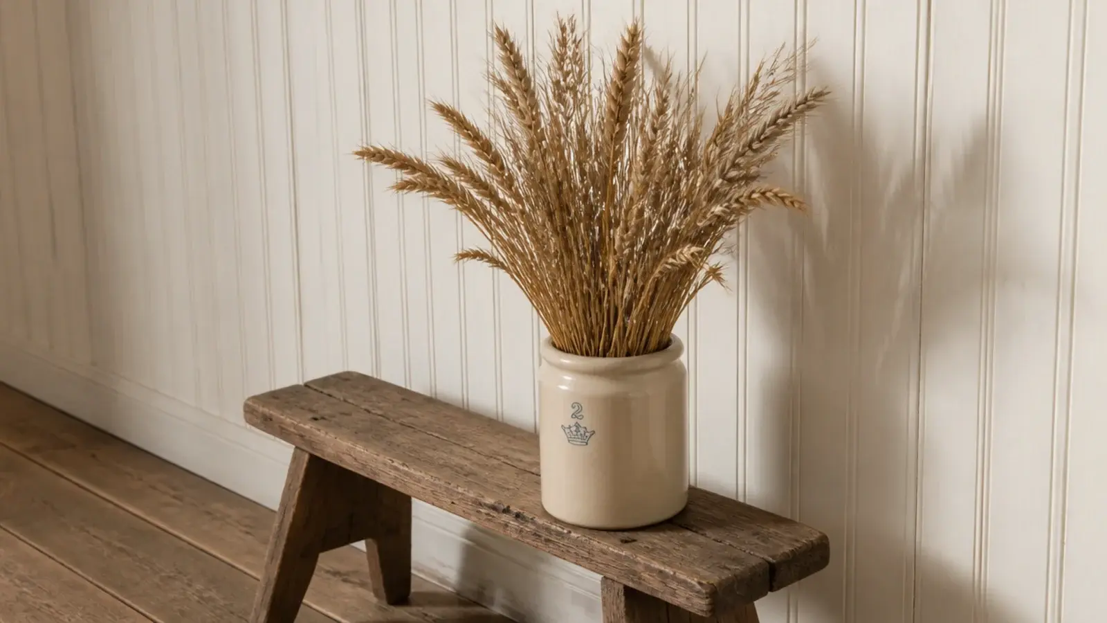 dried wheat stems standing in a stoneware crock in an entryway