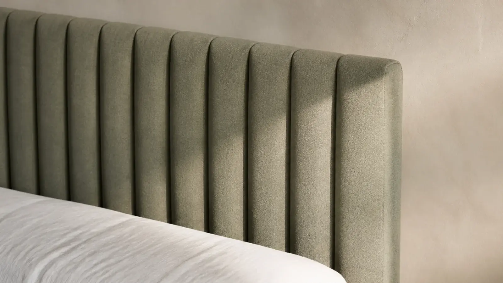 vertical channel tufted headboard in muted sage fabric with even soft ribs