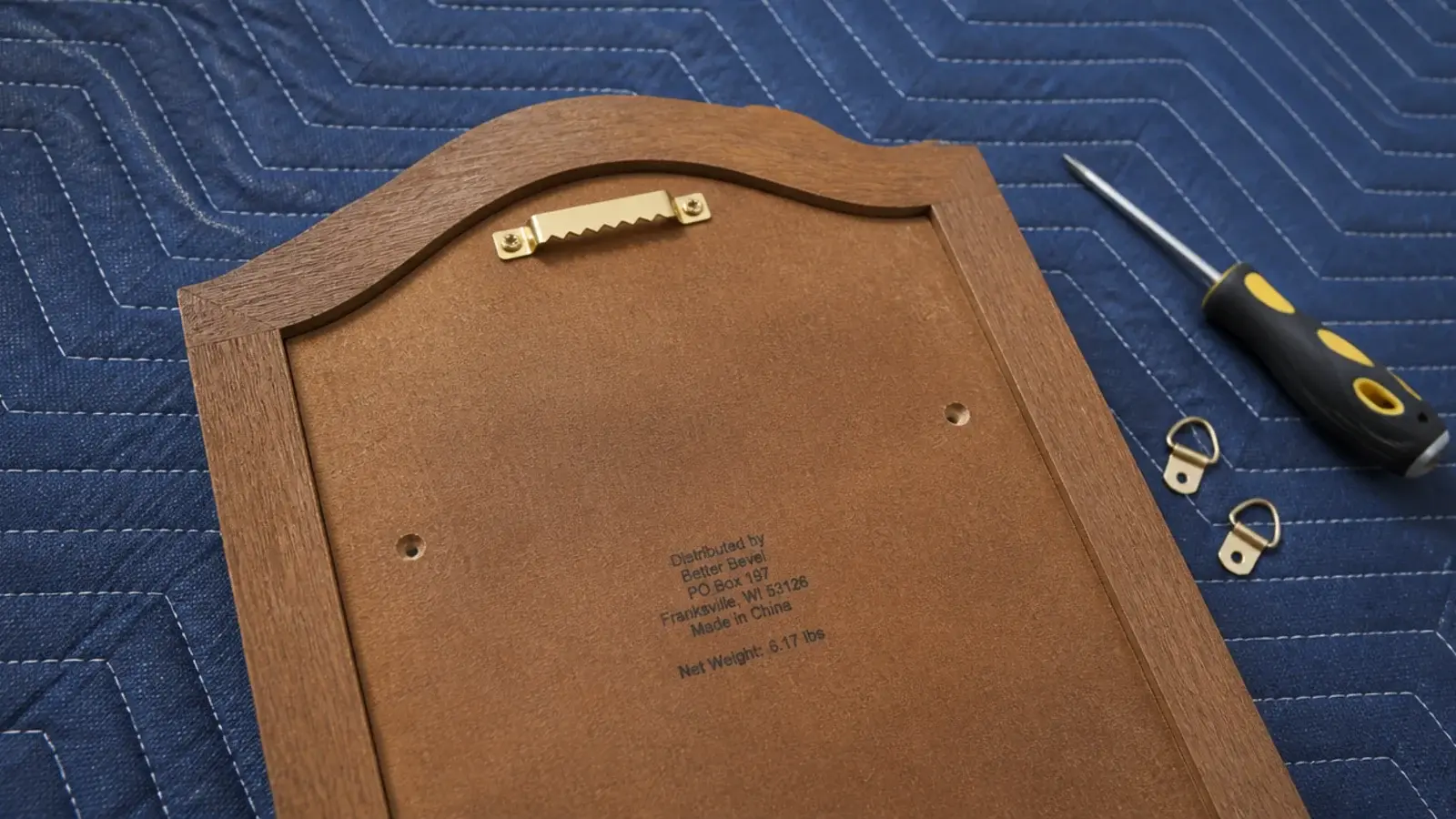 back of a mirror frame showing sawtooth hanger and screw holes