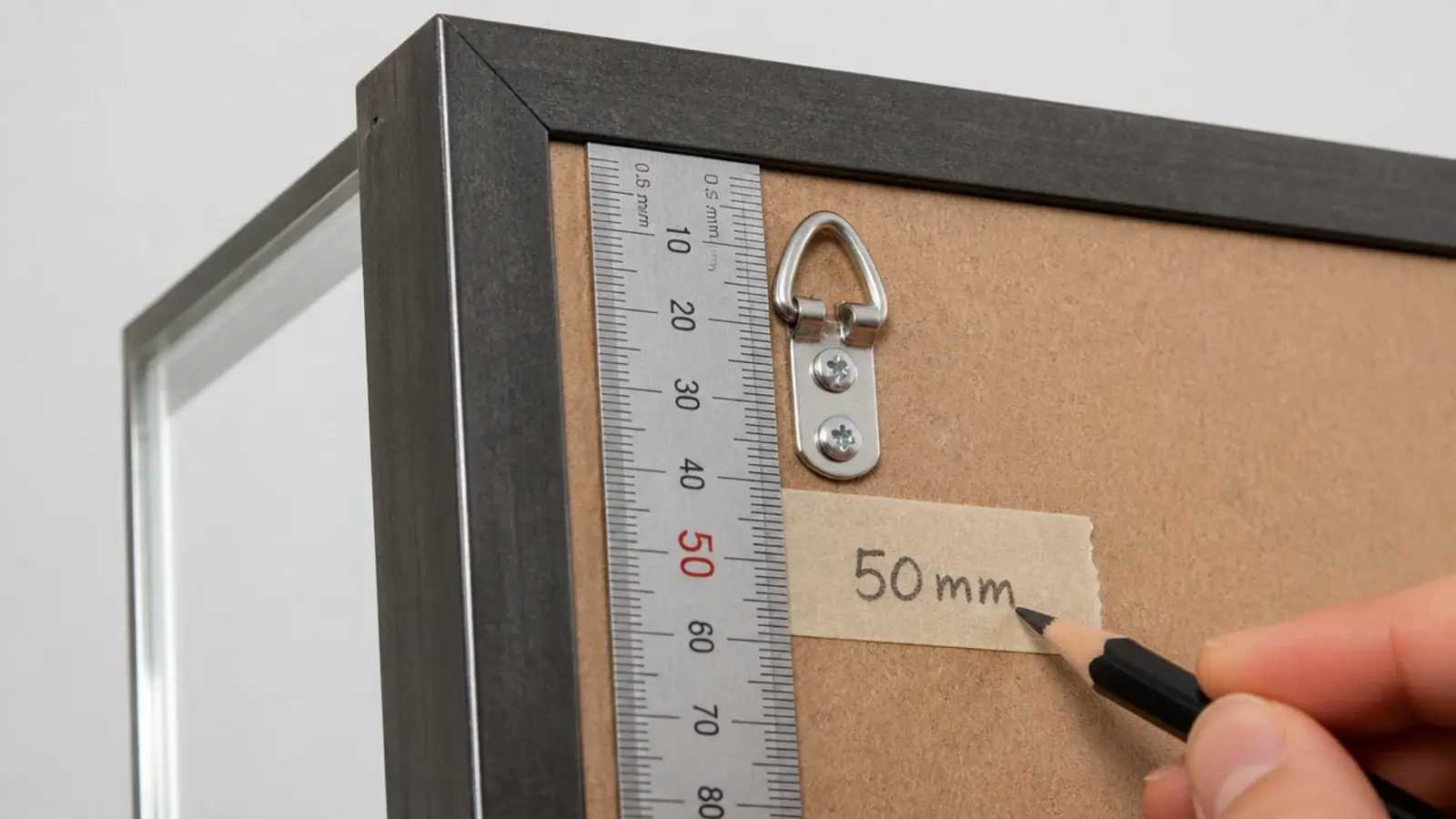 ruler measuring the drop from a mirror frame top to its D-ring