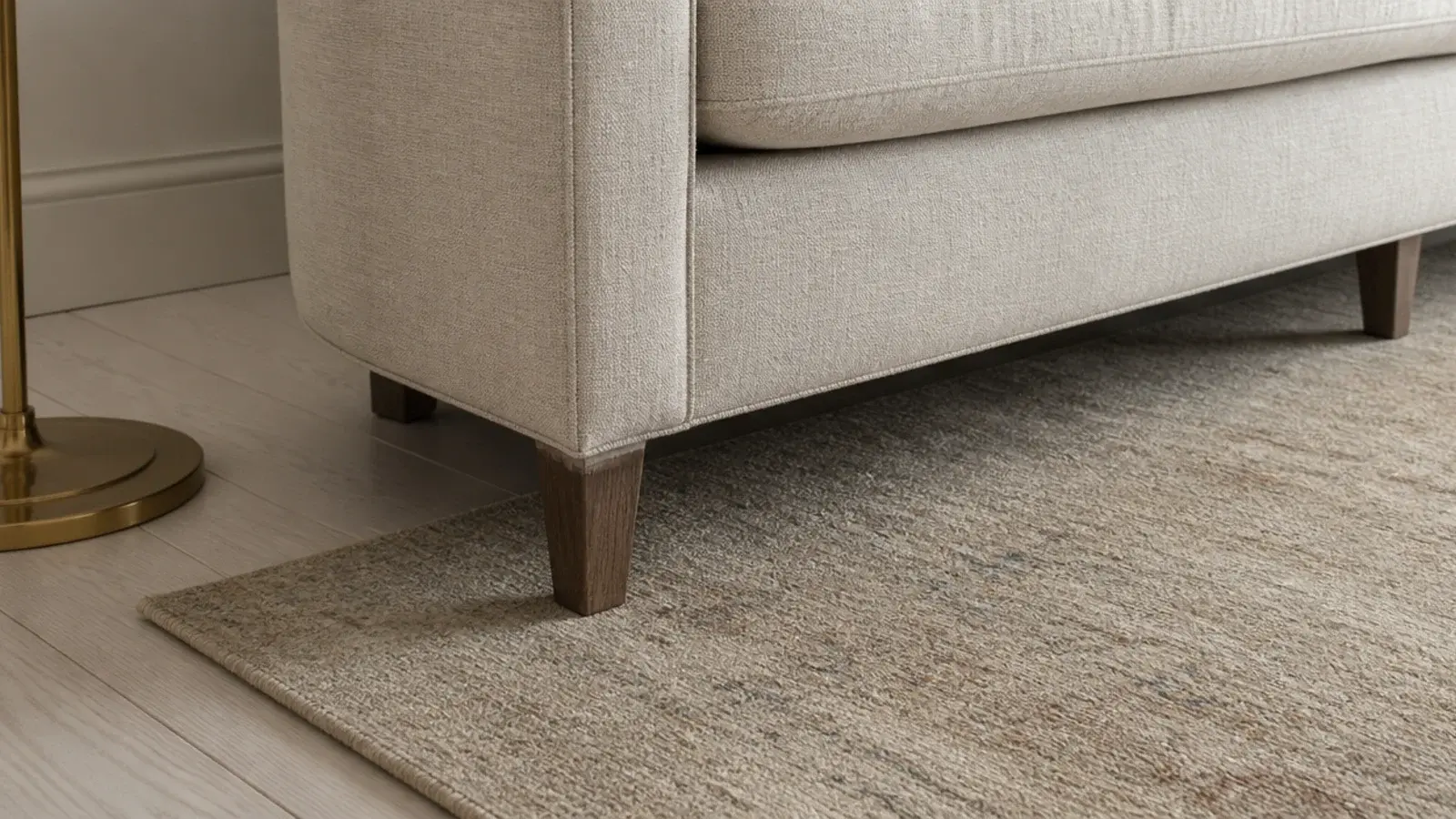 front feet of a long sofa resting several inches onto a rug edge