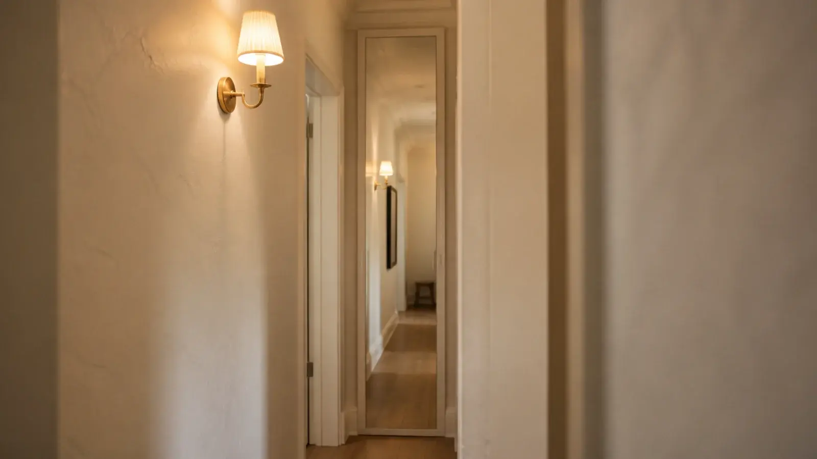 slim shoe cabinet with a mirrored door reflecting a bright narrow hallway