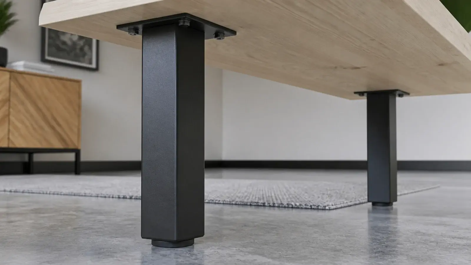 square section black steel desk legs bolted under a pale timber top