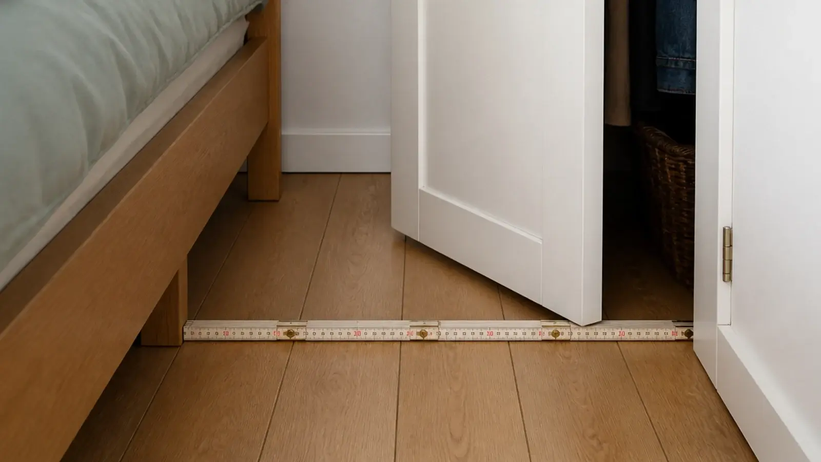 folding rule laid across a narrow gap between a bed and a wardrobe