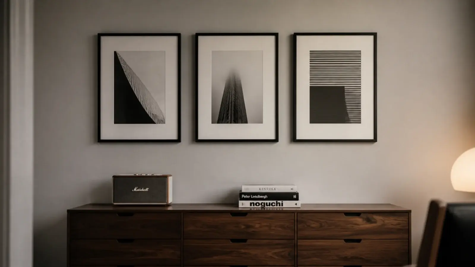 three simple black frames hung in a row above a low chest