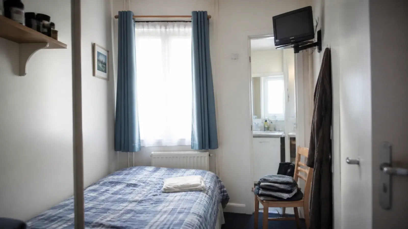 small screen sitting high on a bracket in a very small bedroom