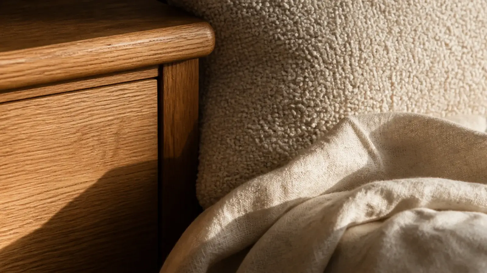 oak cabinet boucle cushion and linen throw layered in one corner
