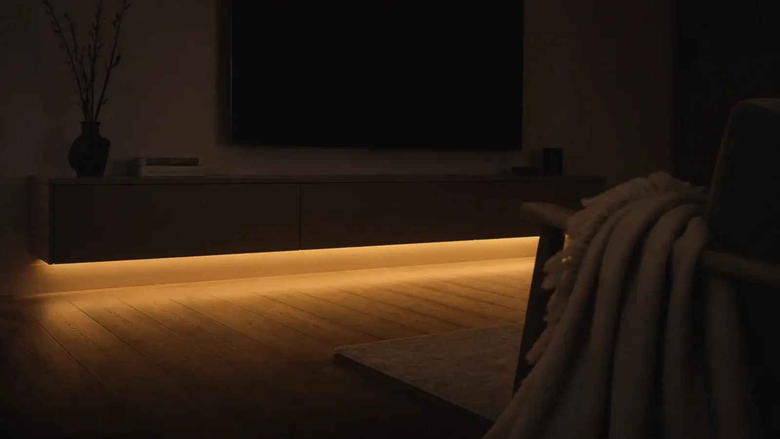warm light spilling from under a media unit onto a wooden floor