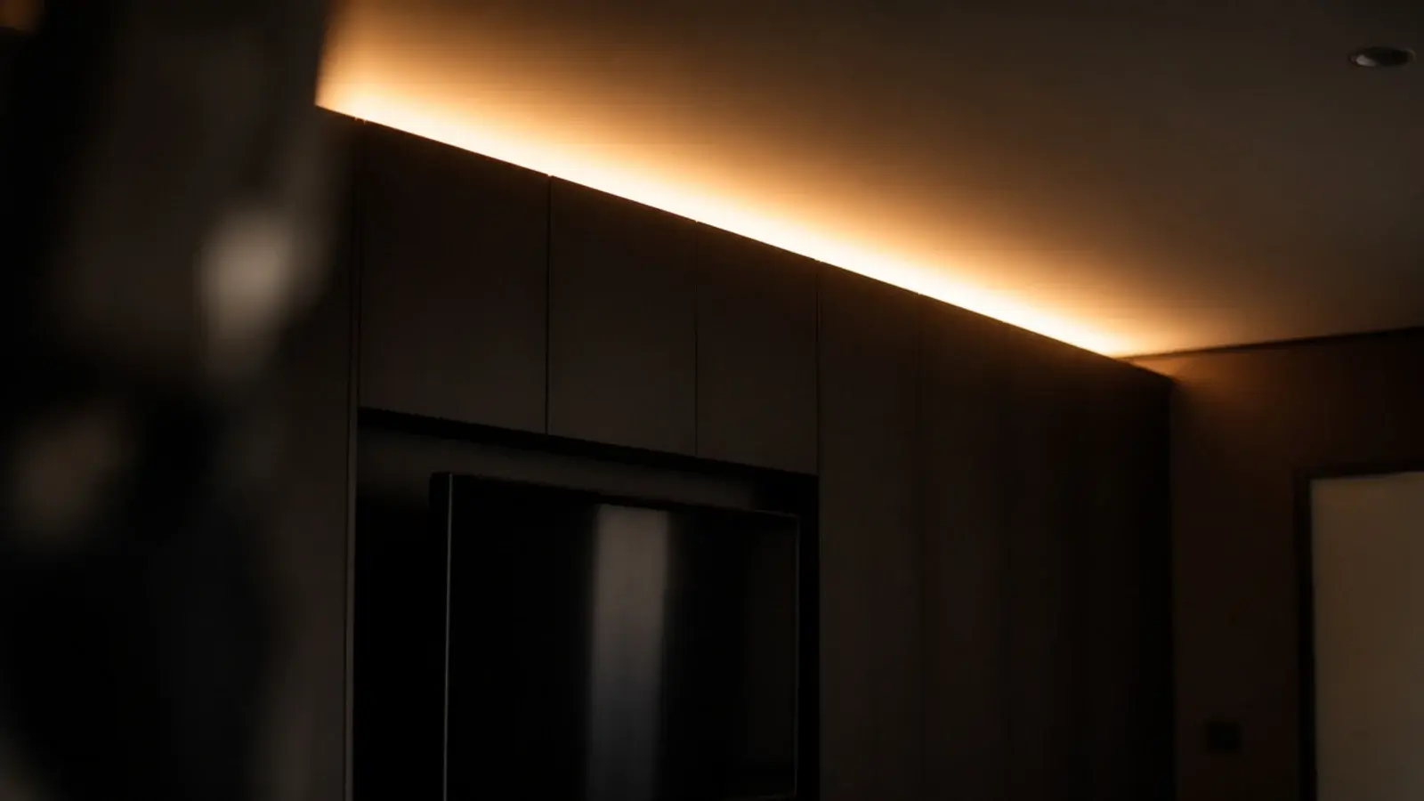 concealed light washing the ceiling above a run of media joinery