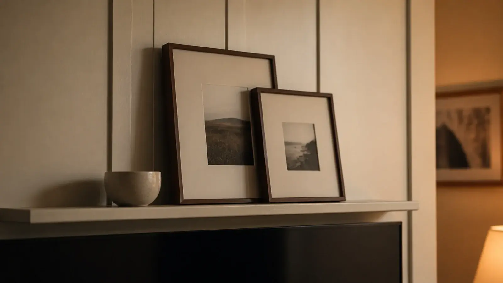 narrow ledge above a television holding leaning frames and a bowl