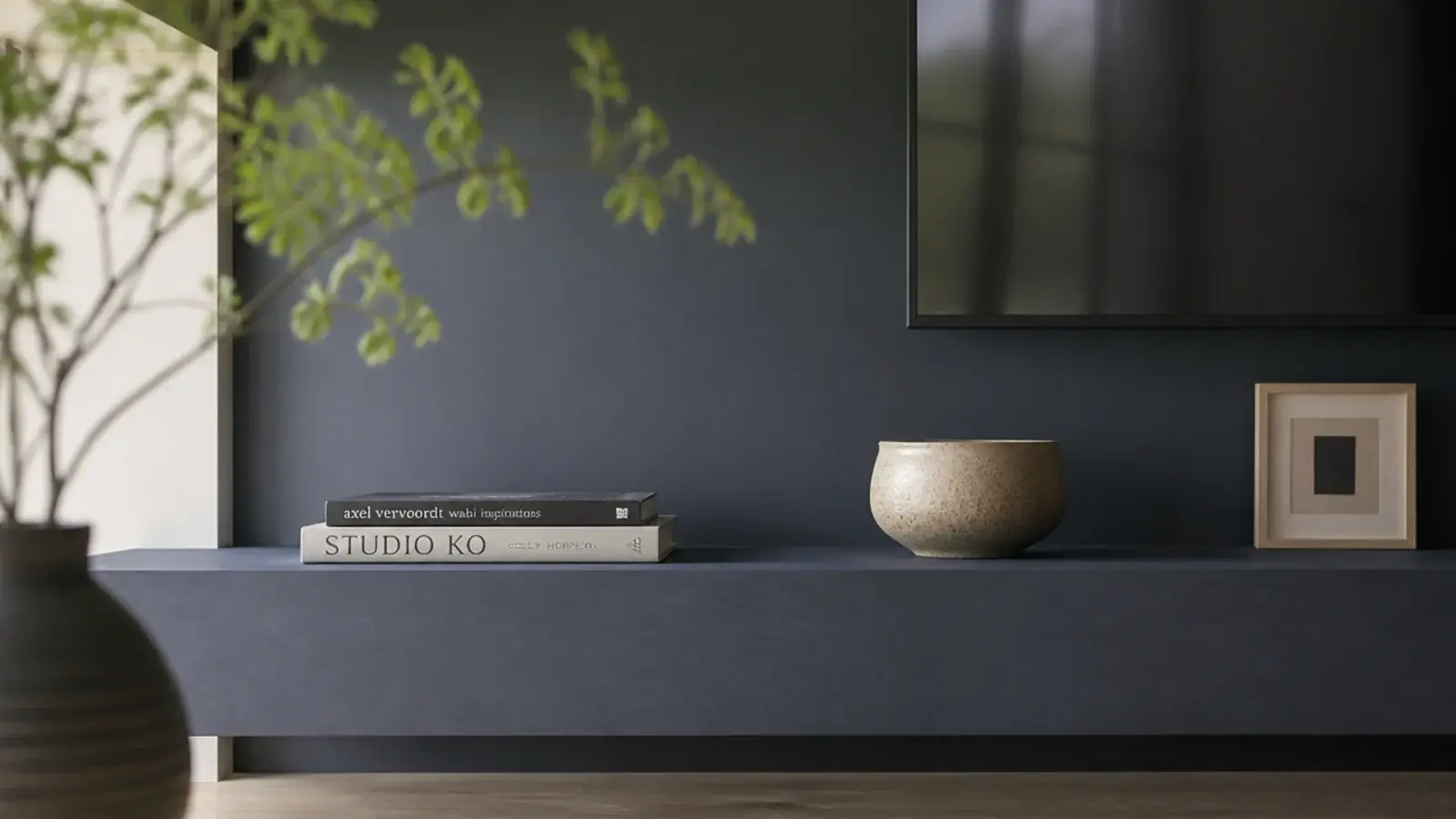 single deep shelf spanning a media wall with three objects on it