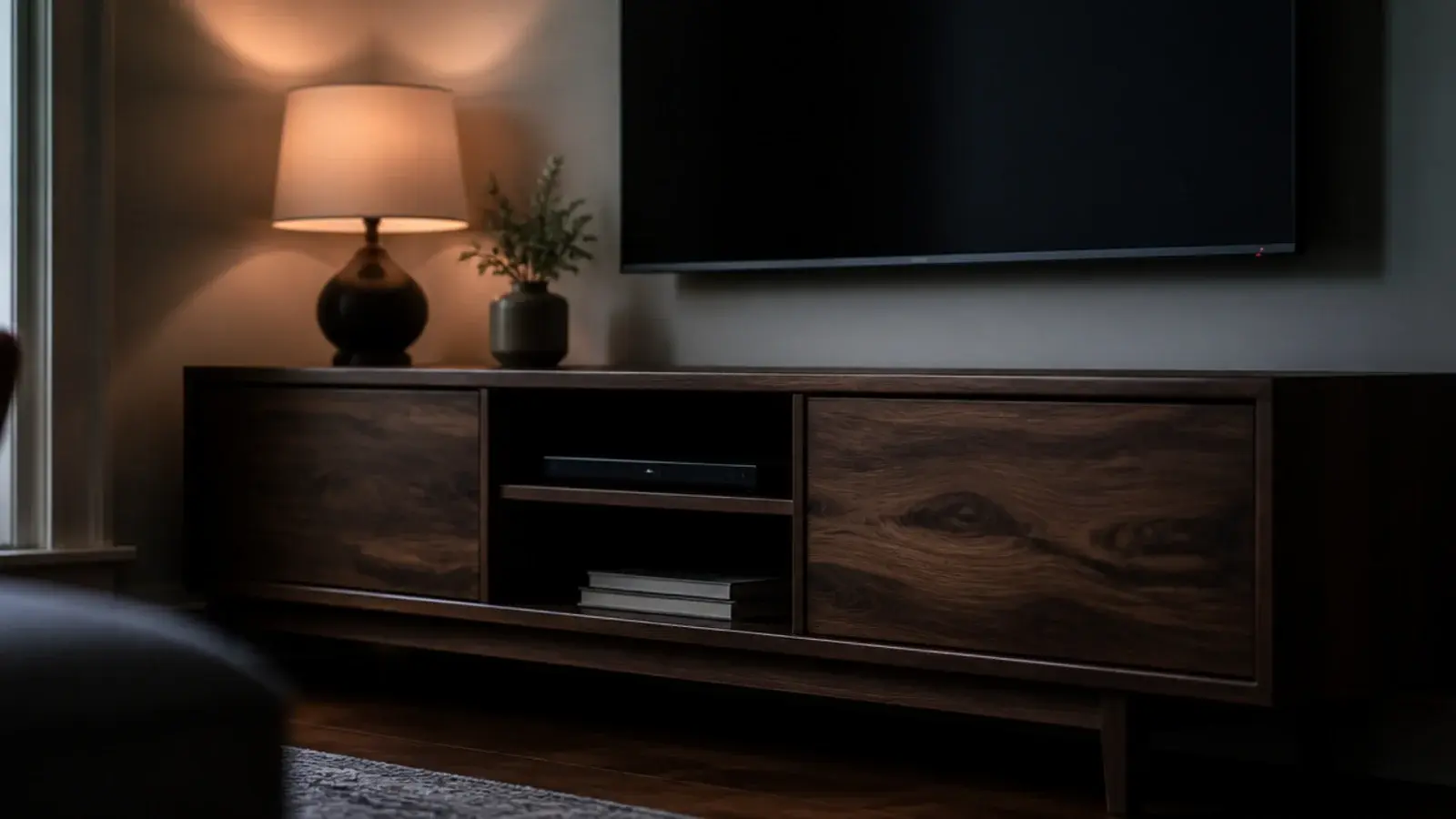 dark walnut media cabinet glowing warm in a dim living room corner