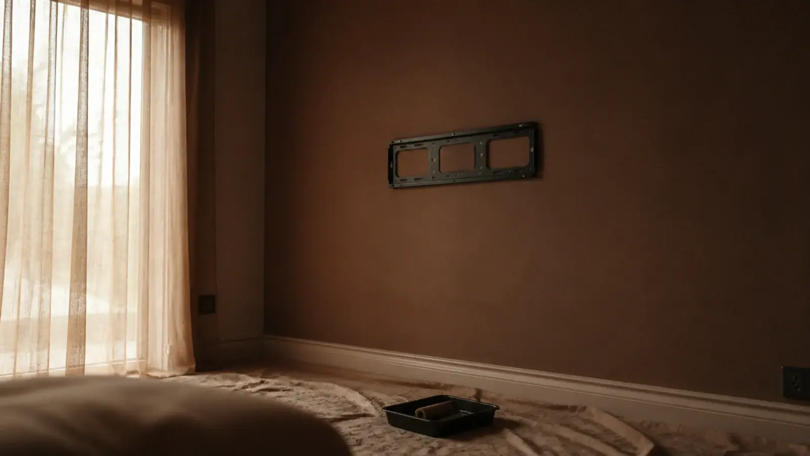 freshly painted deep clay feature wall drying behind a bare screen mount