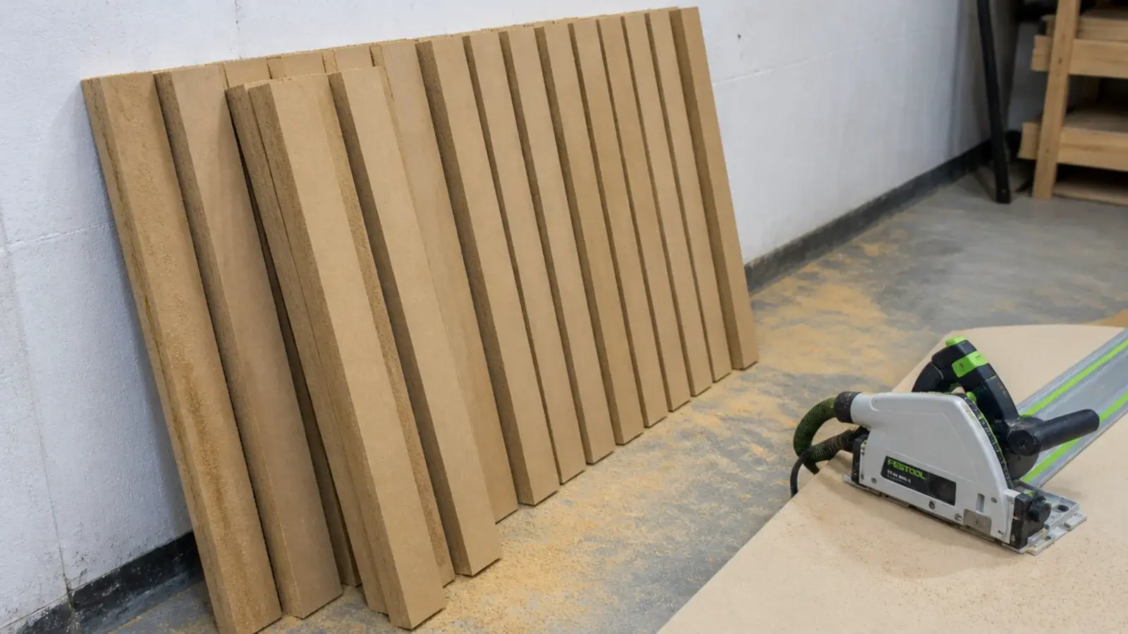 stack of freshly ripped mdf battens leaning against a workshop wall