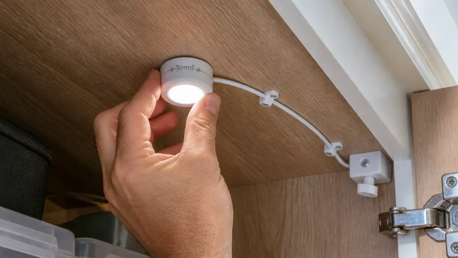 small puck light being fitted to a stair soffit inside storage