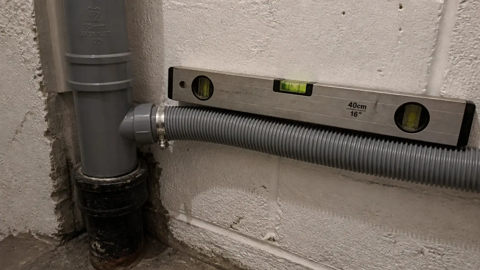 grey waste pipe running into a cast iron soil stack in a cellar