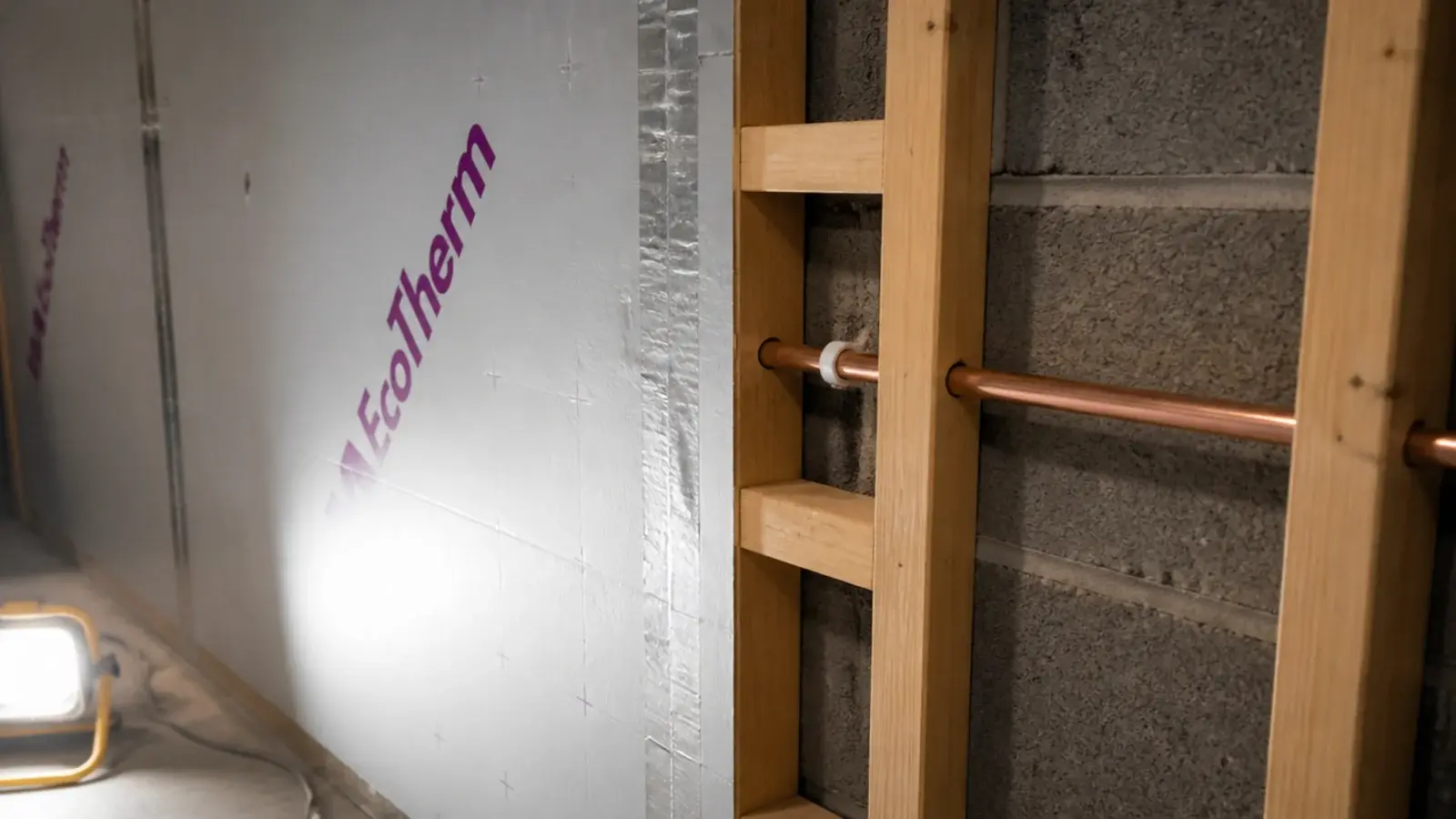 insulated plasterboard fixed over basement block wall with a service void