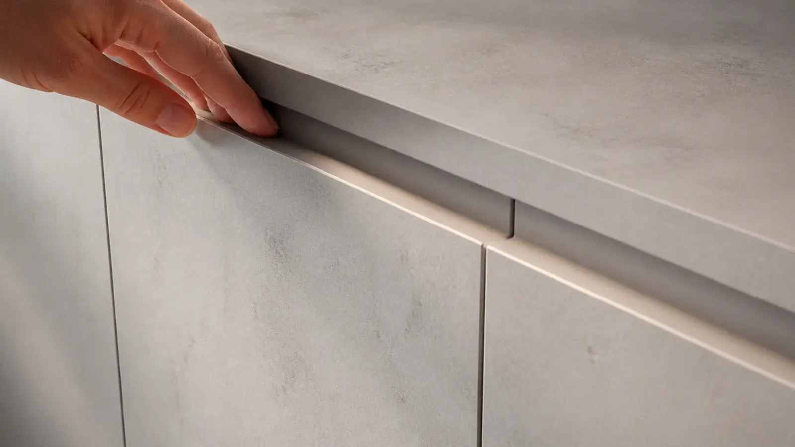 continuous J-pull recess running along the top edge of slab cabinet doors