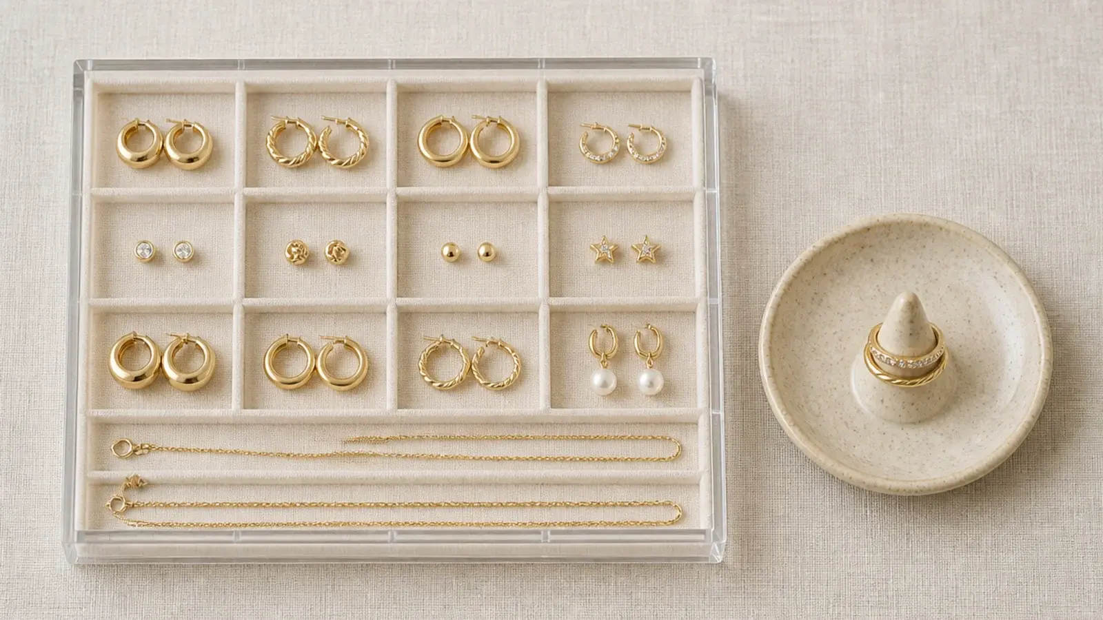 acrylic jewelry tray with compartments holding earrings rings and chains
