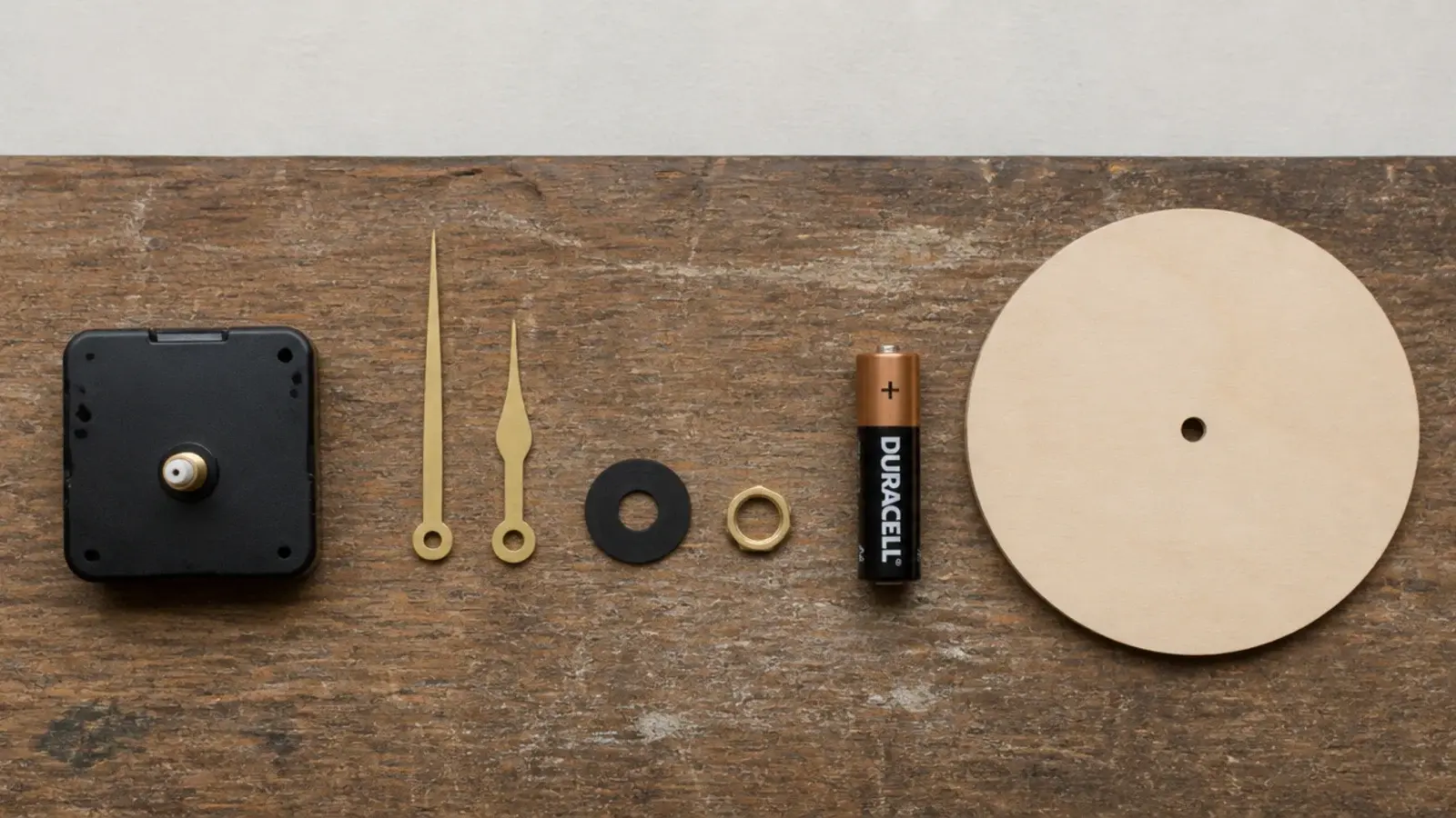 quartz movement hands and washers laid out beside a blank dial